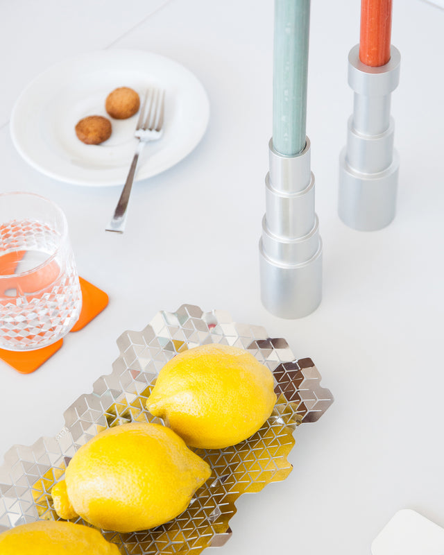 Aluminum candle holders displayed in a table setup and natural light, showcasing their minimalist design, high quality material and detailed craftsmanship.